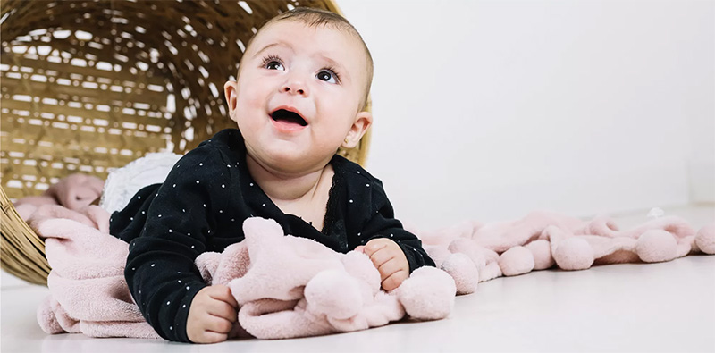 A baby enjoying a soft plush blanket, highlighting comfort, safety, and gentle materials suitable for infants.