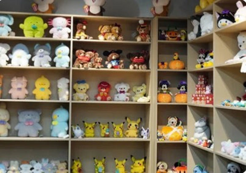 A wide variety of plush characters arranged on wooden shelves, showcasing diverse designs for retail or showroom presentation.