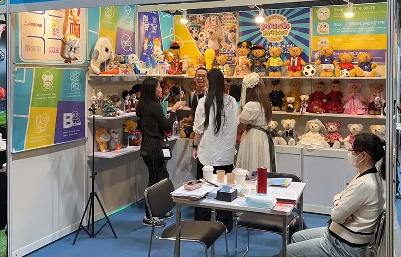 Plush toys showcased at an exhibition booth, highlighting brand displays and business discussions with potential buyers.
