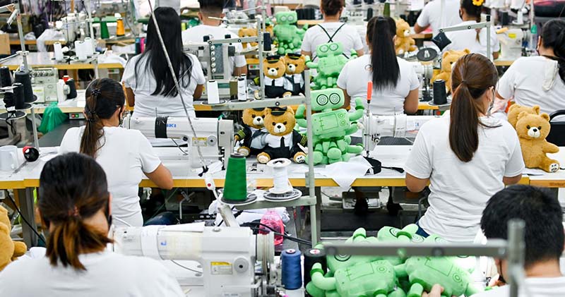 Operators sew and assemble plush toys at industrial sewing stations to ensure efficient and consistent production.