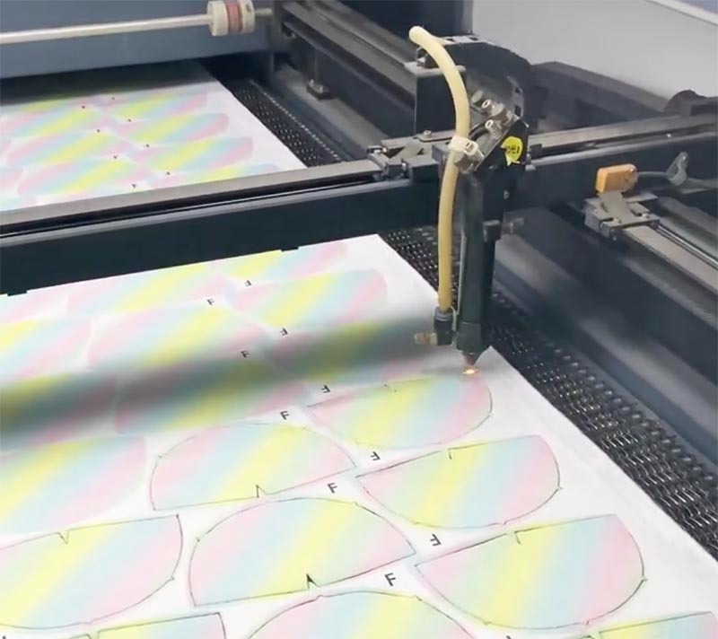 An automated cutting machine precisely cuts printed fabric panels used for plush toy manufacturing. The image highlights the efficiency and accuracy of modern production equipment in preparing pattern pieces for sewing and assembly.
