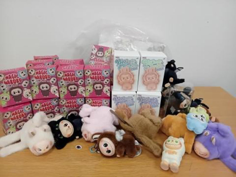 A display of plush dolls and boxed character products arranged on a table, showing retail-ready packaging alongside loose plush items prepared for sale or distribution.