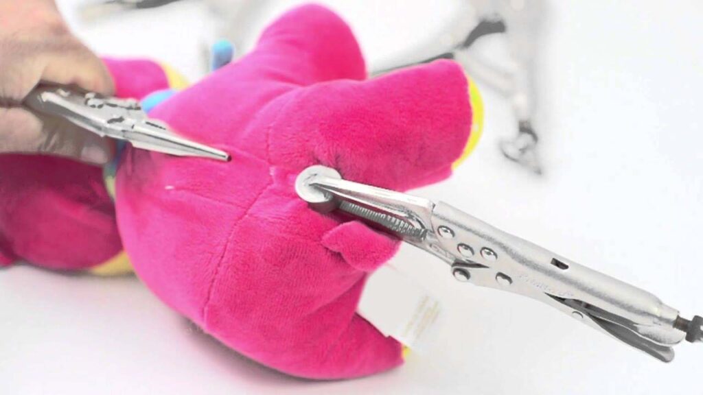 A close-up of tools attaching a plastic safety eye to a plush toy, showing a step in the stuffed animal assembly process.