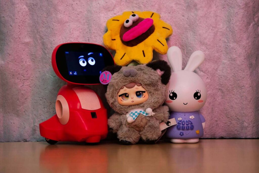 A group of toys including a smart robot toy, plush dolls, and a rabbit-shaped electronic toy, displayed together as modern children’s play companions combining technology and soft toys.