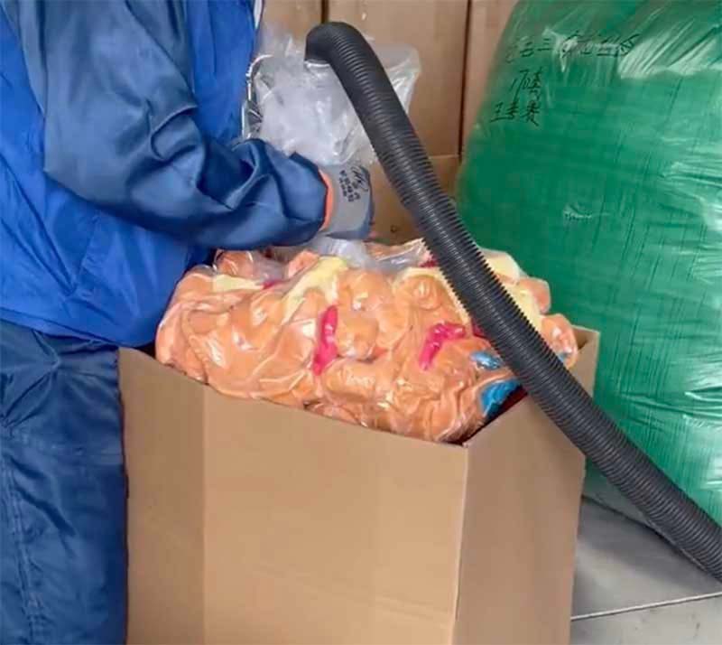 A worker uses vacuum packaging equipment to compress plush toys inside a large carton for bulk shipping and storage. The image highlights a space-saving packaging method commonly used in plush toy manufacturing to reduce shipping volume and improve transport efficiency.