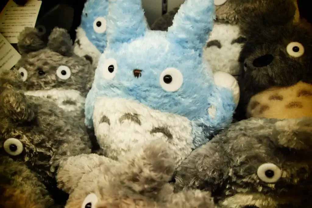 A collection of soft character plush toys with distinctive round eyes and textured fur, inspired by popular Japanese animation style designs and displayed closely together for retail presentation.