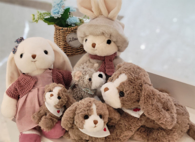 A group of soft rabbit plush toys in different sizes and outfits arranged together, highlighting gentle textures and charming character design.