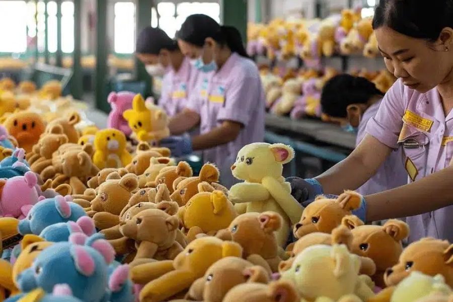 Factory workers assembling and checking colorful teddy bear plush toys on production lines.