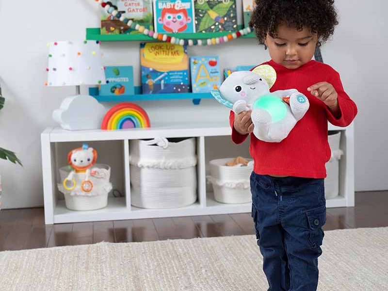 Toddler playing with light-up interactive plush toy in a colorful playroom