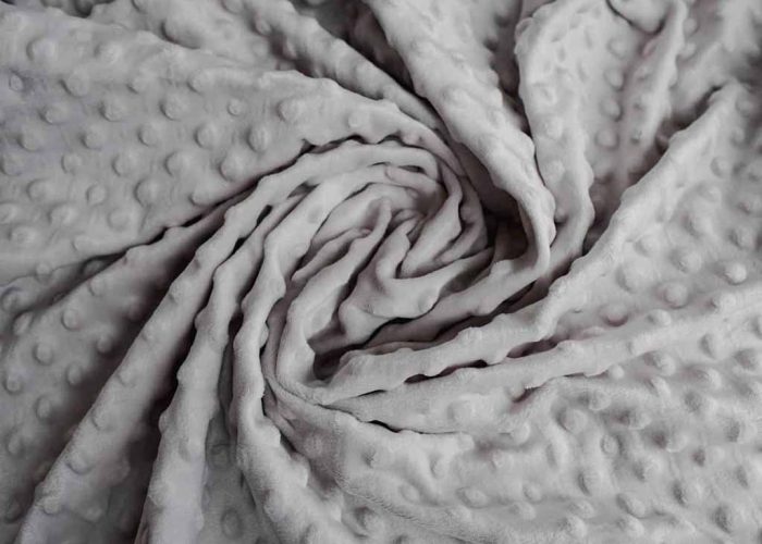 Soft gray minky fabric with raised dot texture, folded to show plush surface and bumpy pattern, commonly used for baby blankets and plush toys.