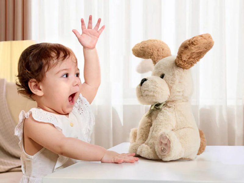 Baby interacting with a plush dog toy on a table indoors