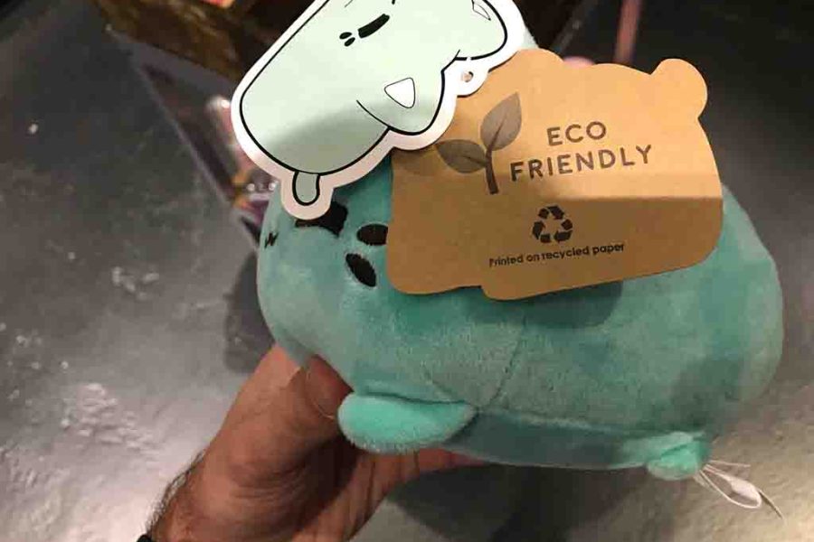 Hand holding eco-friendly plush toy with recycled paper tag.