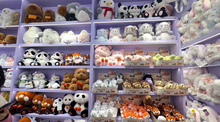 Wide assortment of plush animals arranged on pastel-colored shelves, showcasing variety and organized retail presentation.