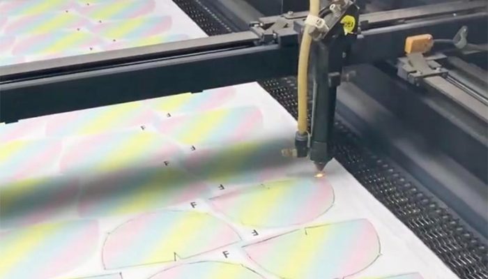 An automated cutting machine precisely cuts printed fabric panels used for plush toy manufacturing. The image highlights the efficiency and accuracy of modern production equipment in preparing pattern pieces for sewing and assembly.