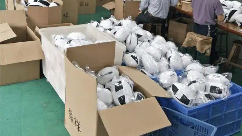 Workers packing finished plush toys into cartons and plastic bags in a factory setting, preparing bulk orders for shipment.