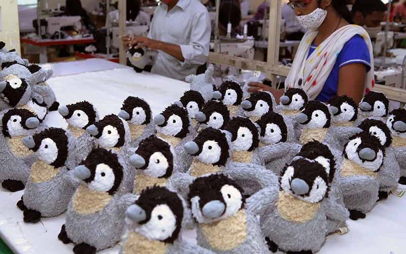 Workers inspecting and assembling penguin plush toys on a factory production line, ensuring quality control before packaging.
