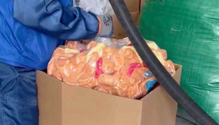 A worker uses vacuum packaging equipment to compress plush toys inside a large carton for bulk shipping and storage. The image highlights a space-saving packaging method commonly used in plush toy manufacturing to reduce shipping volume and improve transport efficiency.