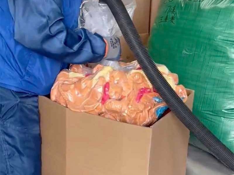 A worker uses vacuum packaging equipment to compress plush toys inside a large carton for bulk shipping and storage. The image highlights a space-saving packaging method commonly used in plush toy manufacturing to reduce shipping volume and improve transport efficiency.
