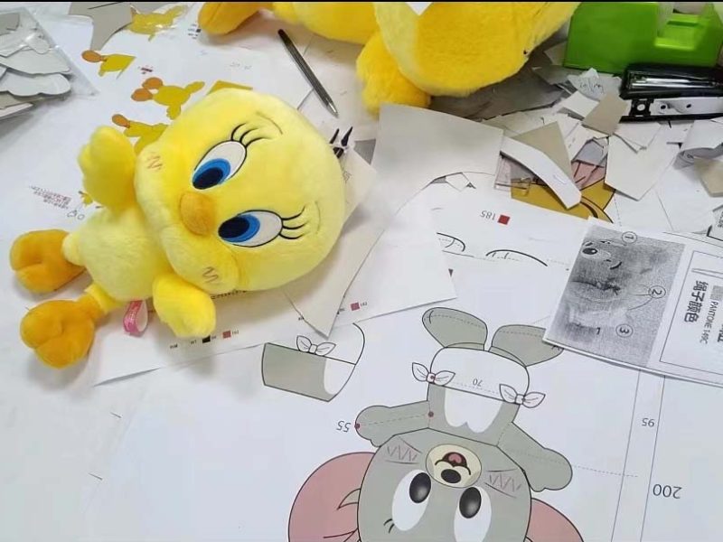 A plush toy sample placed alongside pattern drawings and cut pieces during the development and prototyping stage.