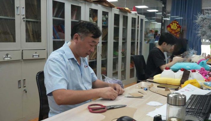Technicians work on patterns and sample details to prepare plush toys for prototype and production stages.