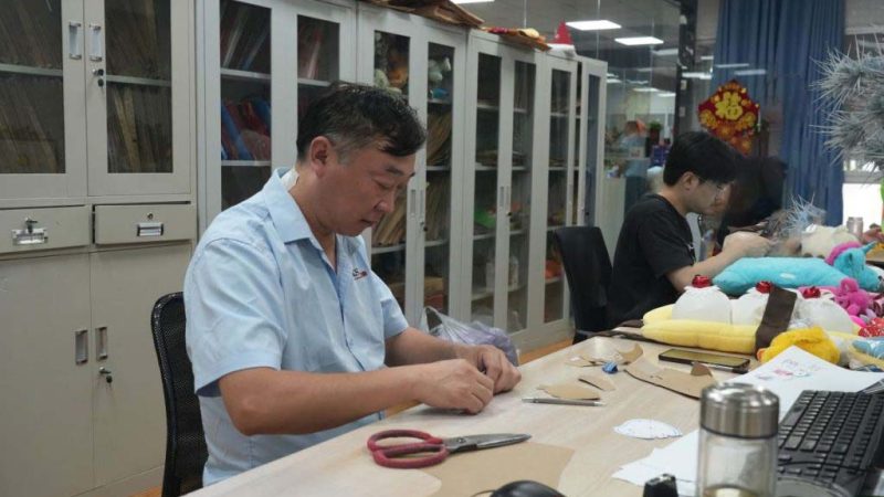 Technicians work on patterns and sample details to prepare plush toys for prototype and production stages.