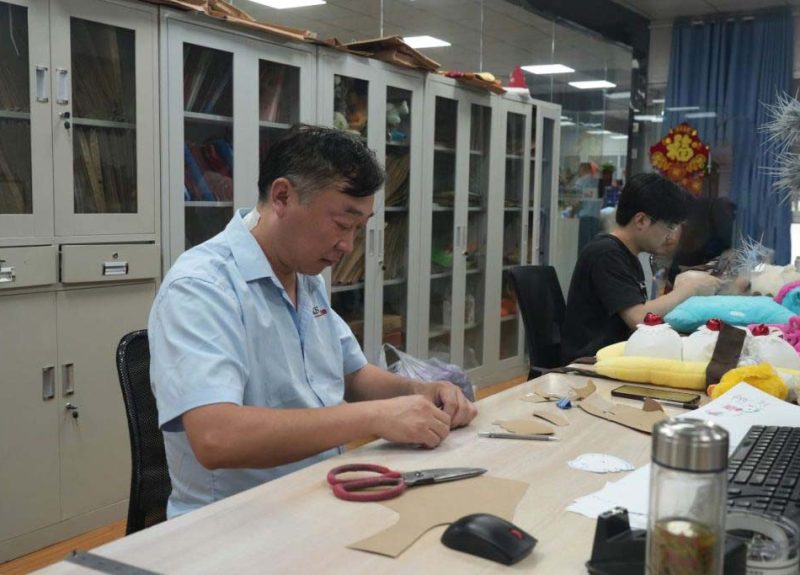 Technicians work on patterns and sample details to prepare plush toys for prototype and production stages.