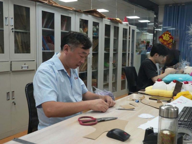 Technicians work on patterns and sample details to prepare plush toys for prototype and production stages.