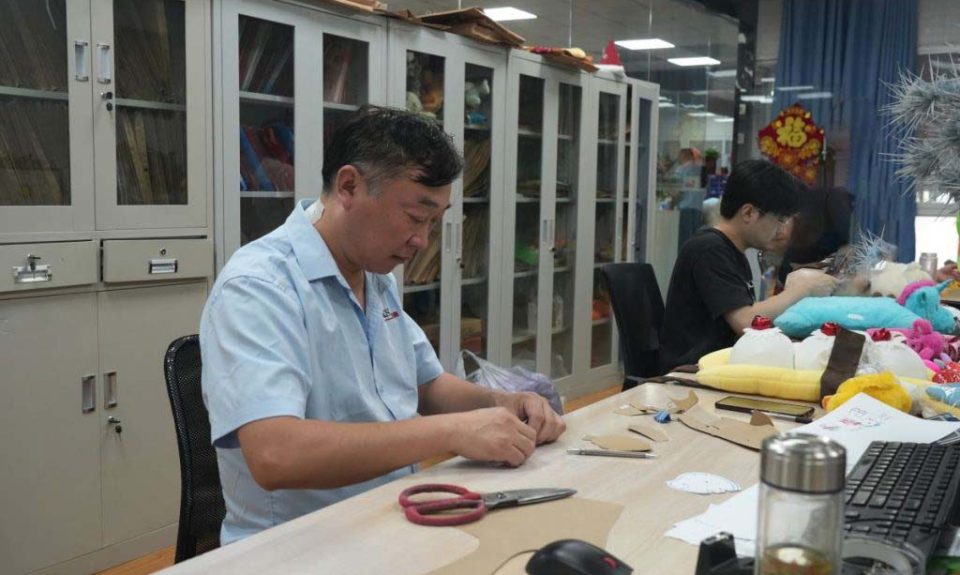 Technicians work on patterns and sample details to prepare plush toys for prototype and production stages.