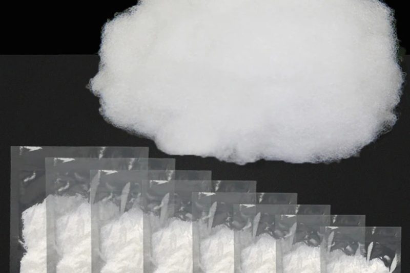 High-elastic polyester fiberfill shown loose and in small sealed packets, used as soft, lightweight stuffing for plush toys and handmade crafts.