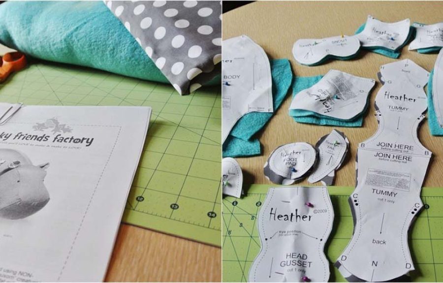Printed plush toy sewing patterns laid out on fabric alongside scissors, tape, and materials for crafting a stuffed animal.
