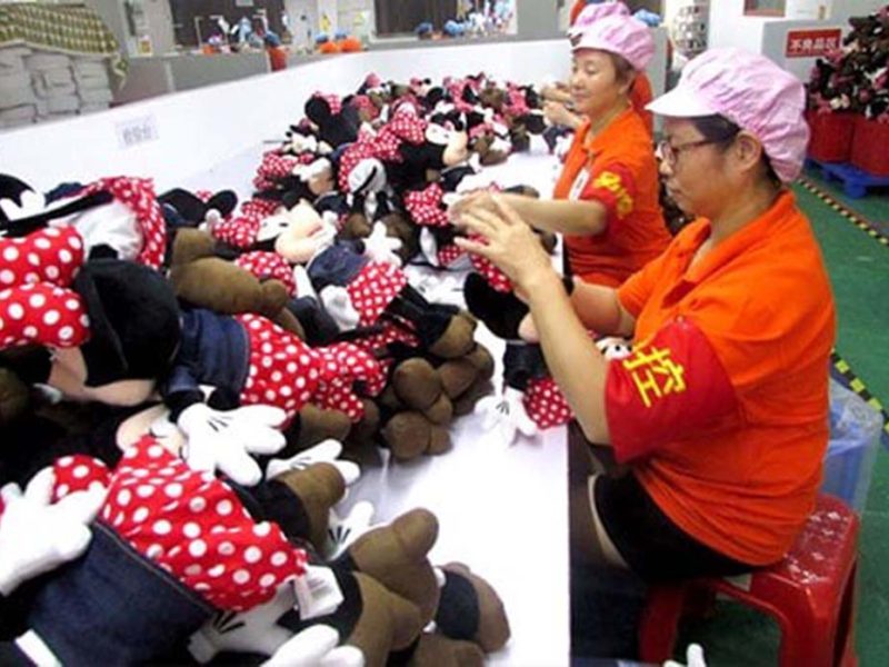Factory workers inspecting and sorting Minnie Mouse plush toys on a production line in China.