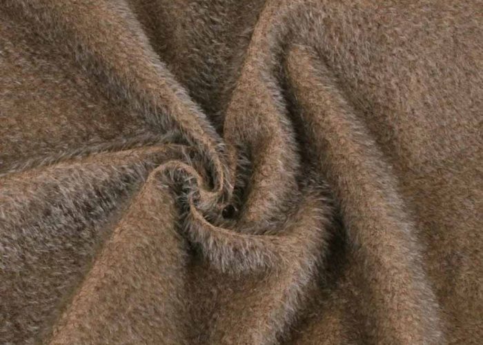 Close-up of brown long-pile plush fabric twisted in a spiral shape, showing its fluffy, soft texture commonly used for stuffed animals and plush toy manufacturing.