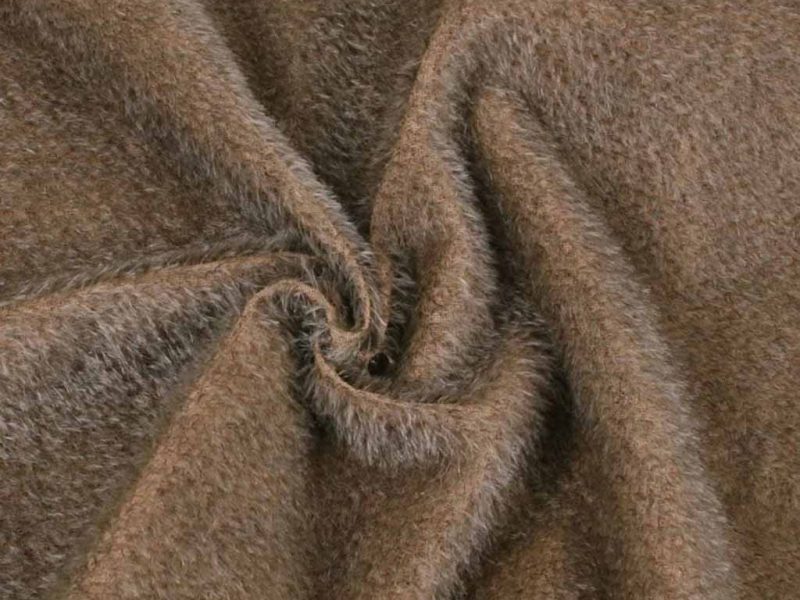 Close-up of brown long-pile plush fabric twisted in a spiral shape, showing its fluffy, soft texture commonly used for stuffed animals and plush toy manufacturing.
