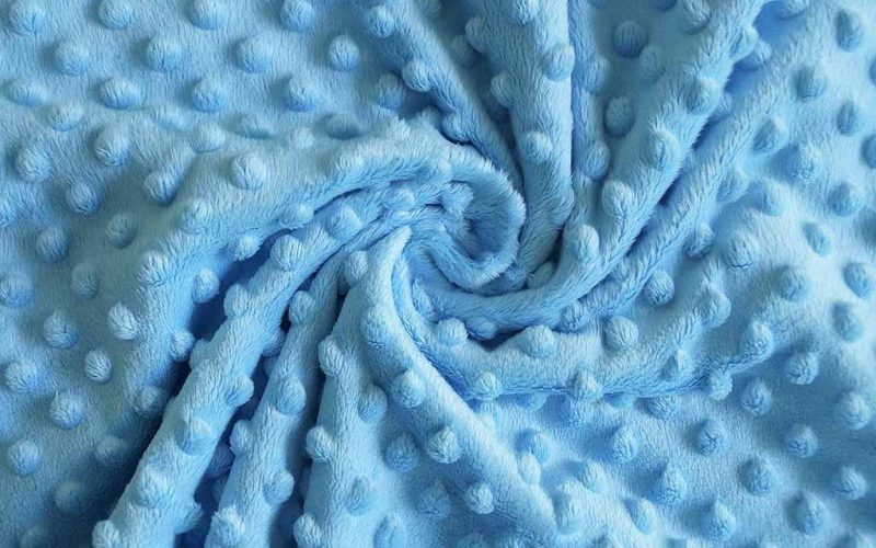 Soft blue minky plush fabric with raised dot texture, commonly used for baby toys and stuffed animals.
